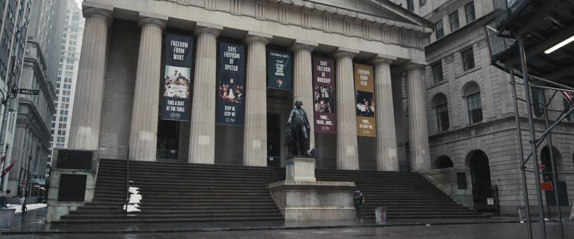 A monument in front of a greek revival style government building in a metropolis on a winter day