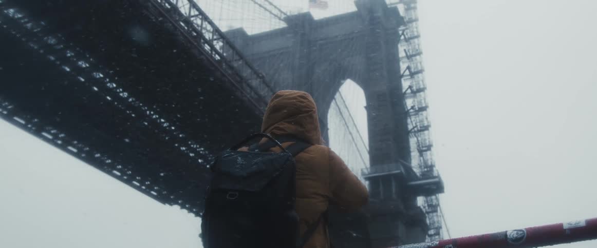 A photographer photographs a large bridge from below during a snowstorm