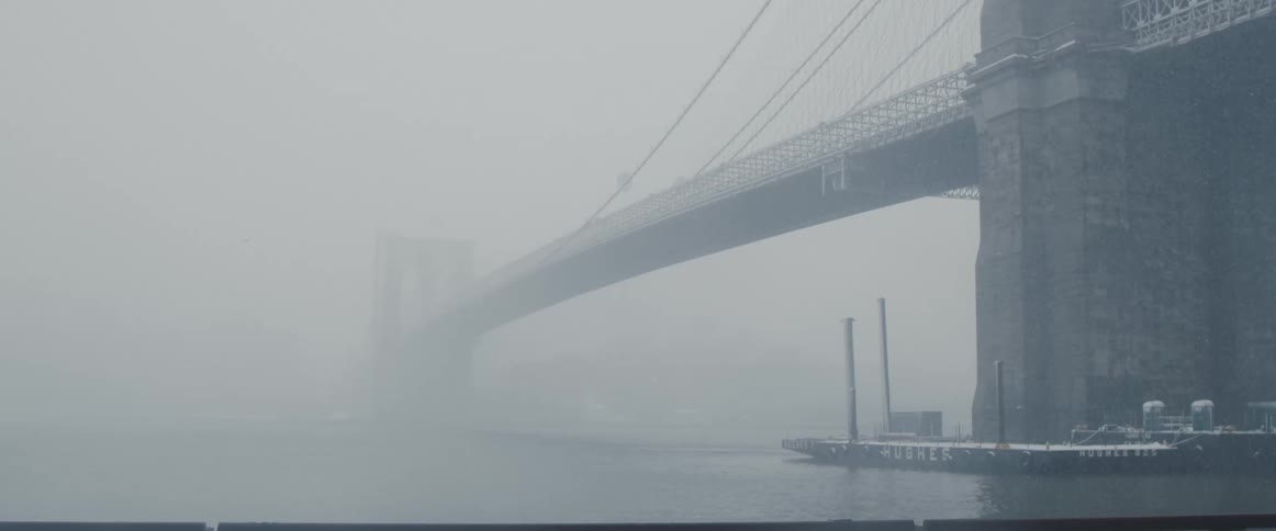 Heavy fog under and around a city bridge with ships in the water