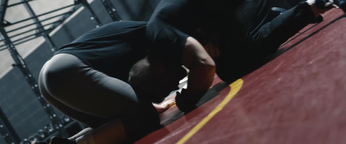 A pair of men wrestle on a mat in a gym