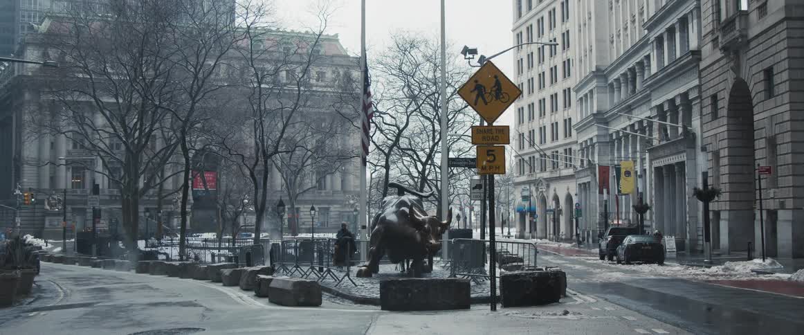 People photograph and look at the charging bull statue in new york while it snows
