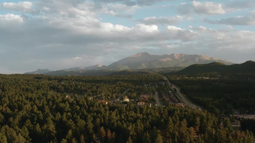 Houses in a forest neighborhood and mountains in the distance under a cloud filled sky