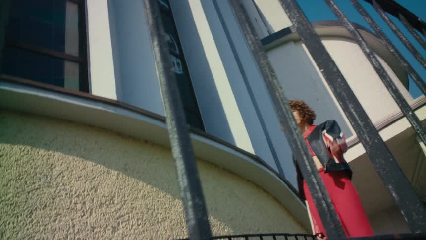 A woman walks along a curved walkway on the side of a building during the day