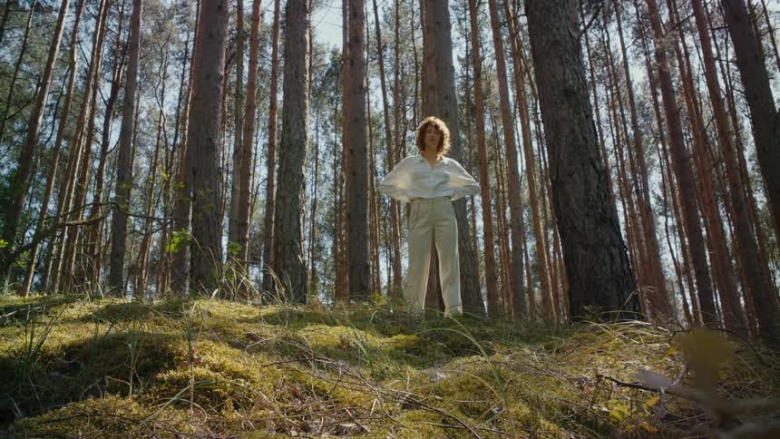A woman stands on the hill by the forest