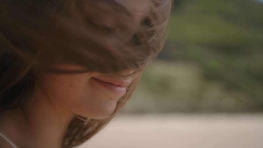 Wind blowing through a womans long brown hair outside