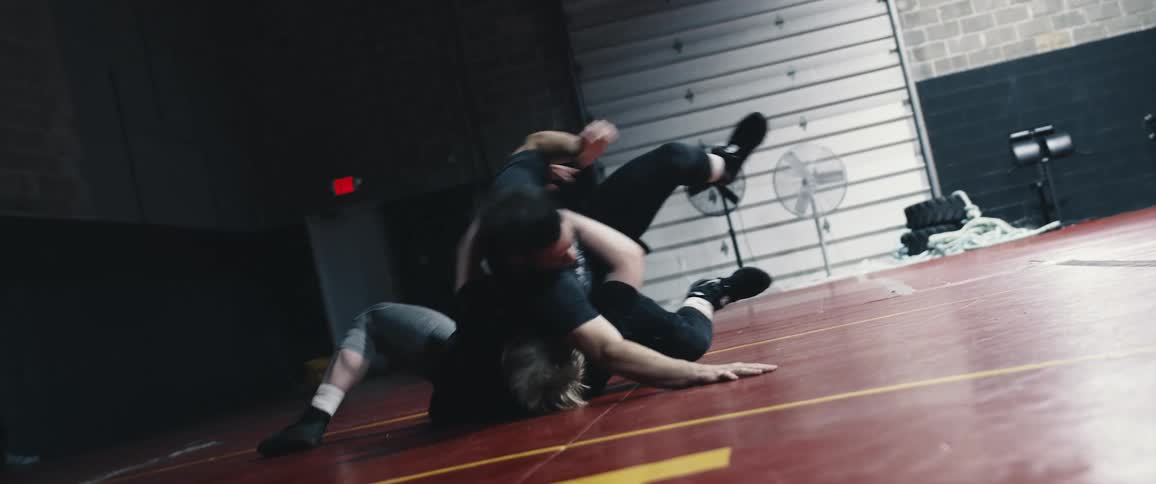 Two men wrestle on a gym floor