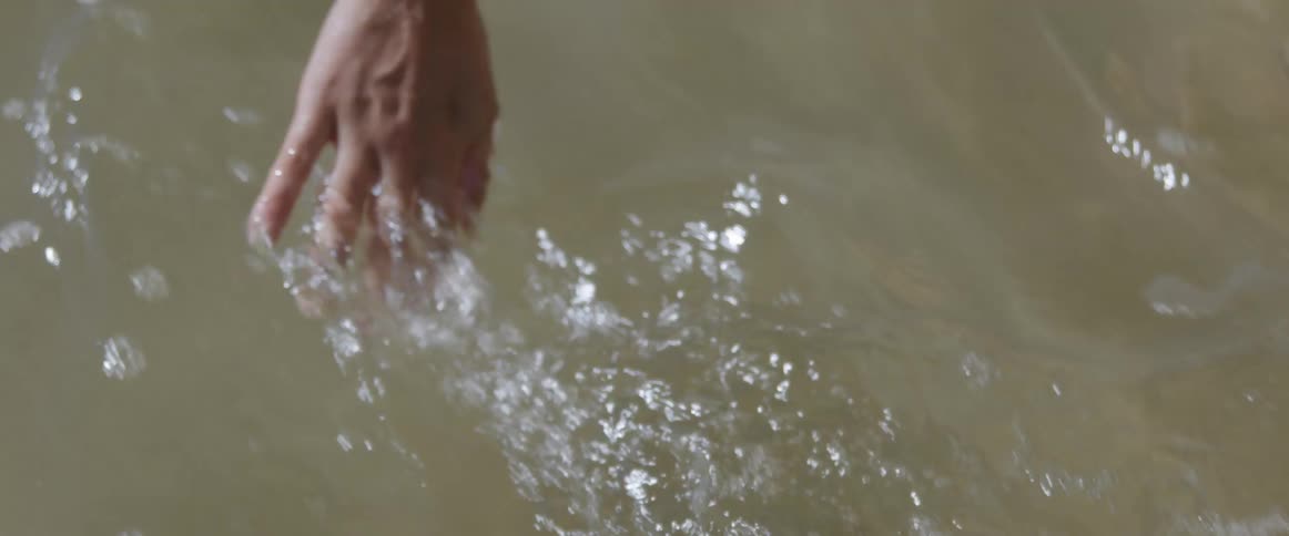 A woman traces her hands through the water