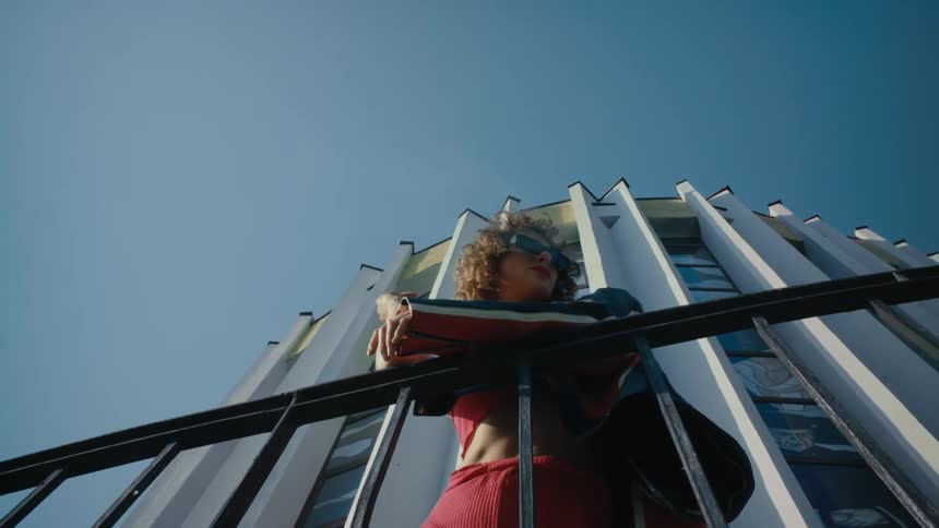 A woman stands outside an office building and smokes a cigarette
