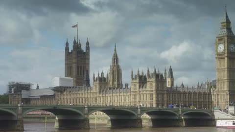 A large building with a clock tower comes into focus on a cloudy day