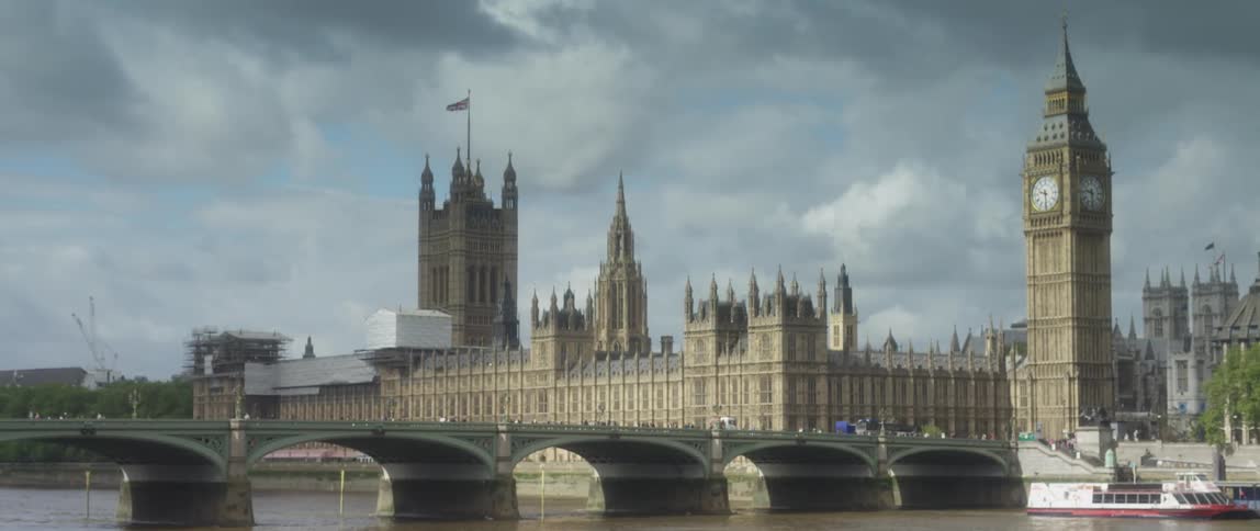 A large building with a clock tower comes into focus on a cloudy day