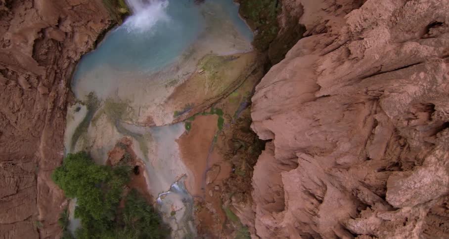 A waterfall cascading into a pool that is surrounded by very steep cliffs
