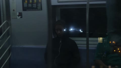 Woman in black hoodie riding on the subway