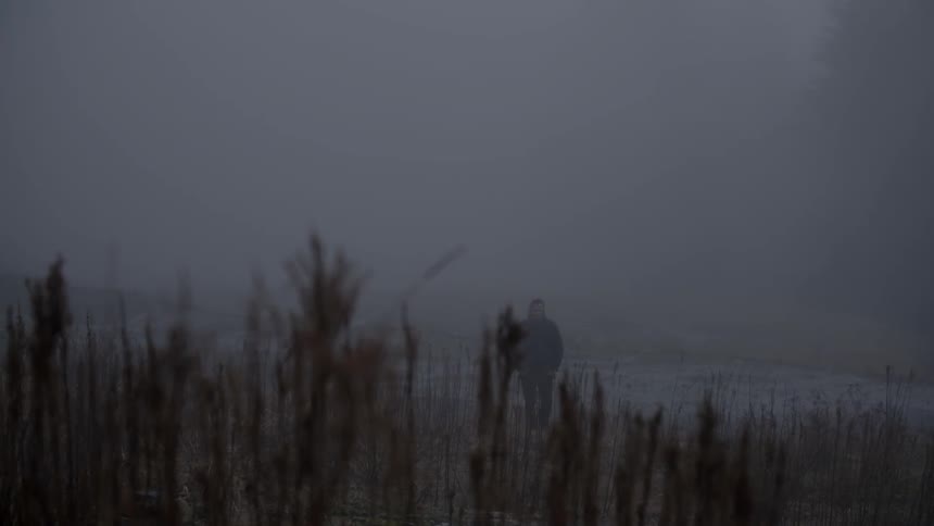A man walks on the beach in the fog