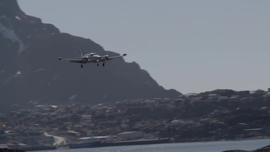 An airplane comes in for a landing near mountains during the day