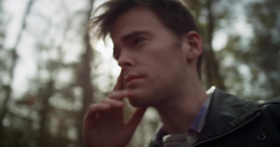 Man wiping his face in the woods