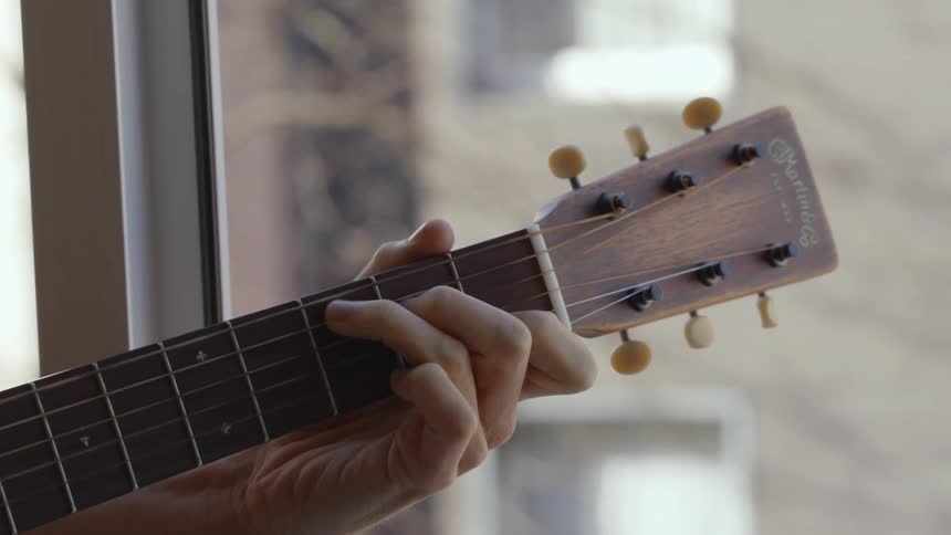 Musician plays guitar near window