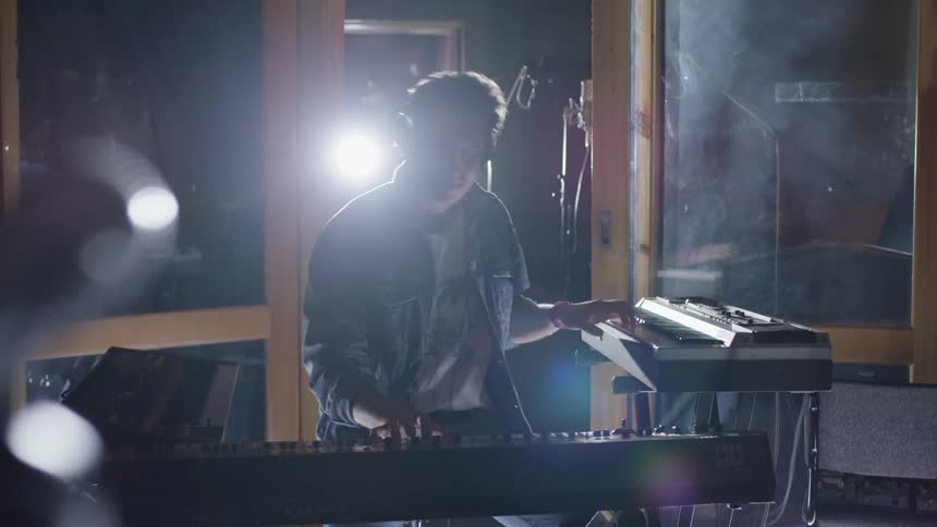 A man is dancing as he plays two keyboards