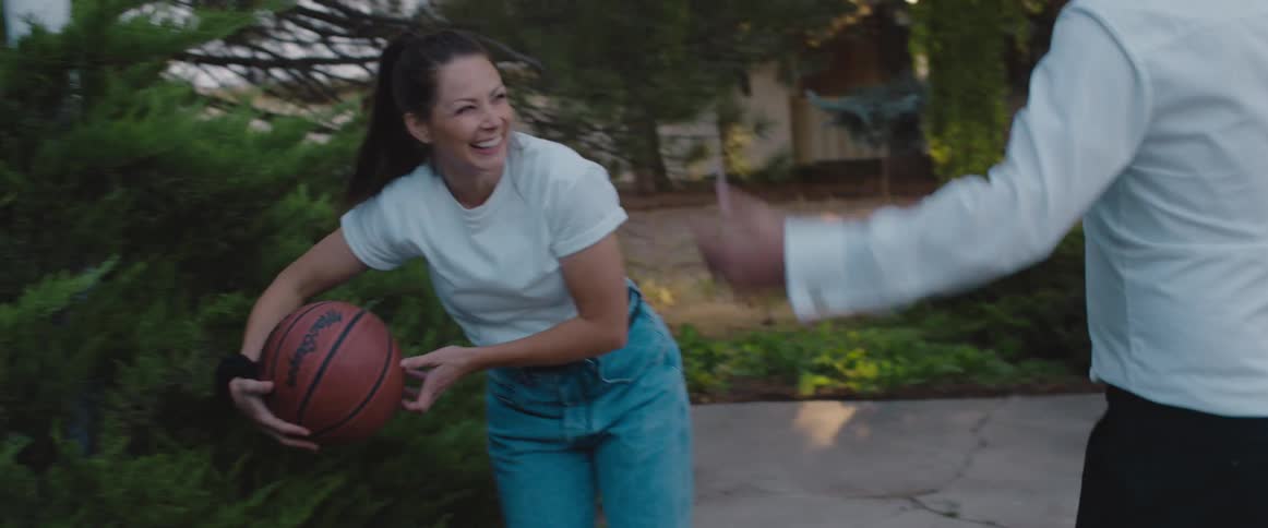 A woman laughs and hugs her husband after scoring the winning basket