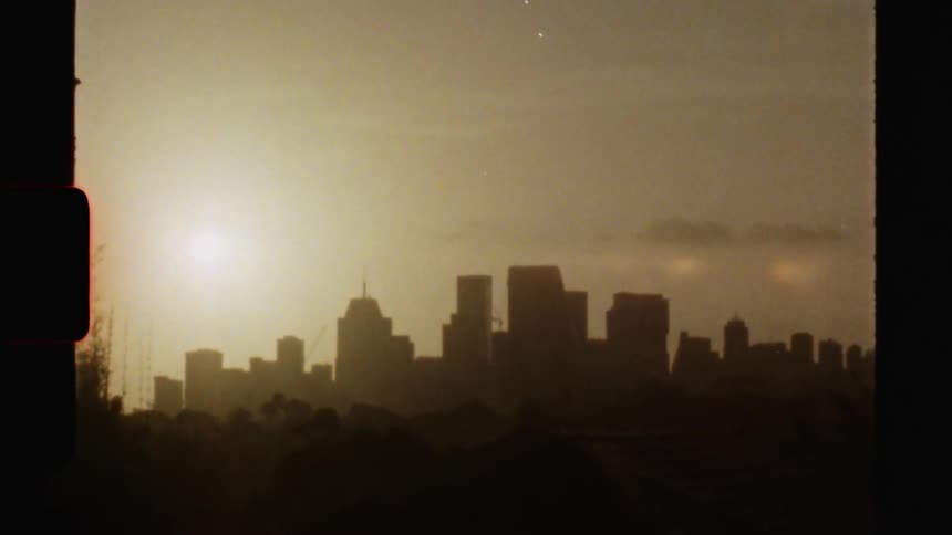 The sun shining in a golden sky behind a city skyline