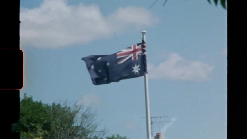 An australian flag blows in the wind outside a building