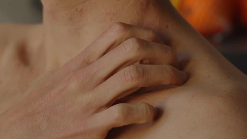 A man lifts his right arm then rubs the area between his neck and left shoulder