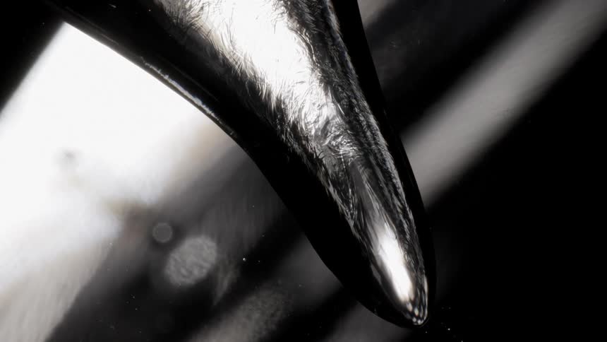 Light shines on a dark liquid like object as it moves