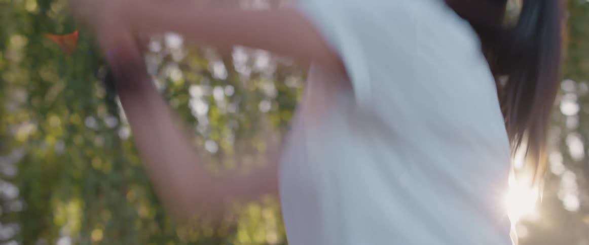 A woman smiles and laughs as she prepares then shoots a basketball outside