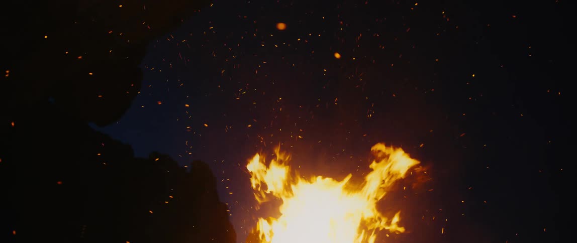 Fire burns and shoots sparks into the dark night