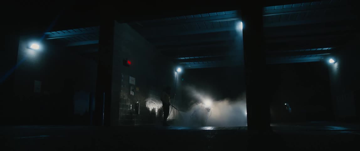 A person washes their motorcycle in a self serve car wash at night