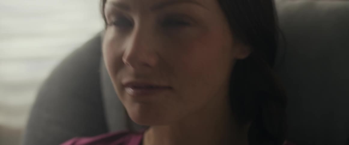 A woman smiles and looks up while rocking her baby