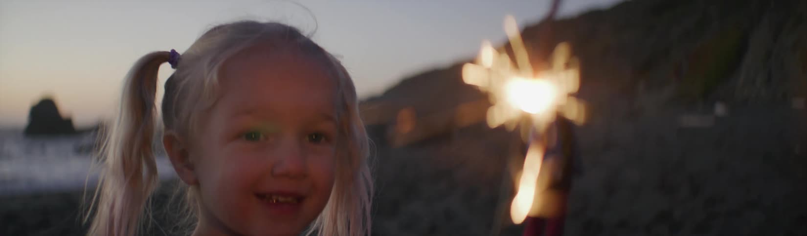 A child playing with a sparkler on the beach
