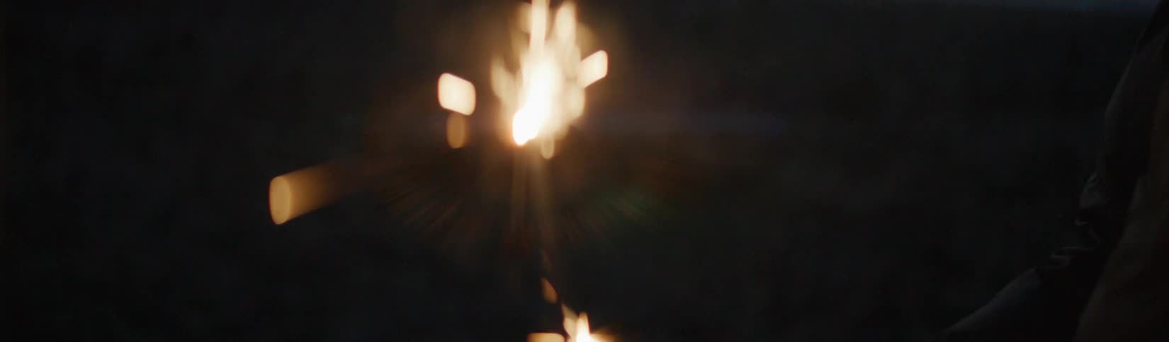 A hand lights a sparkler using a lighter