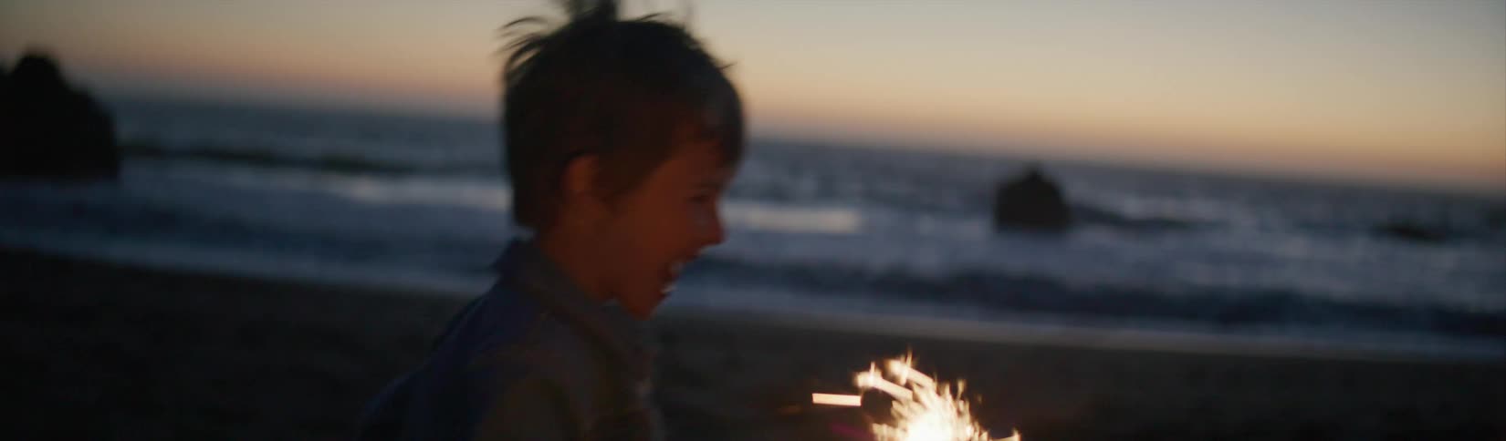 A child running outdoors with a sparkler