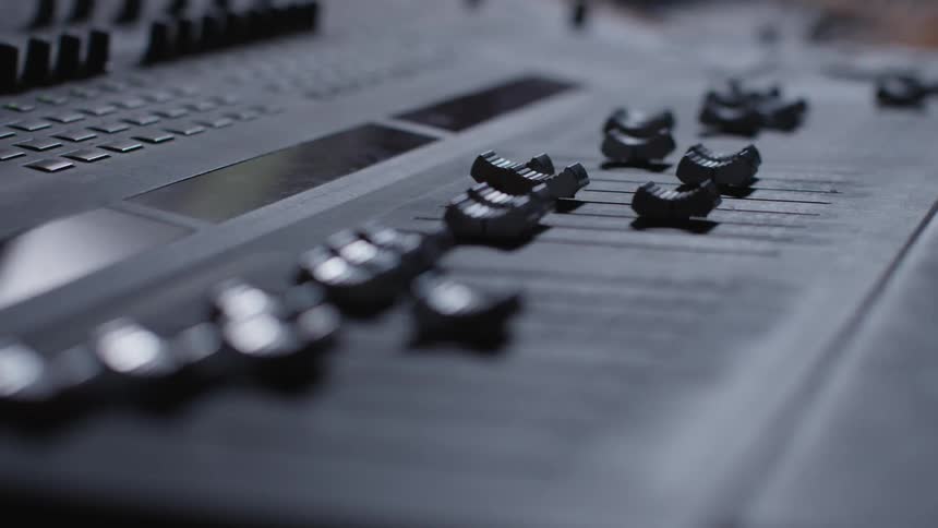 A hand presses a button moving levers on a console
