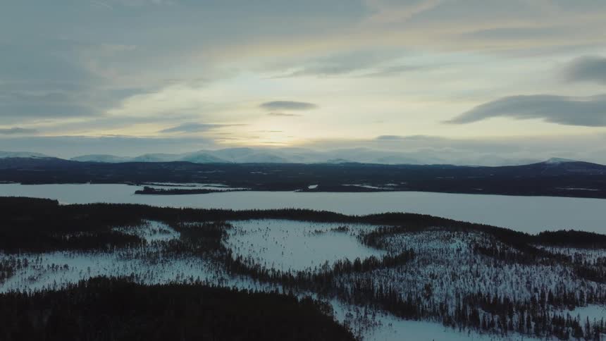 An aerial view of a snowy forest on a cold winter morning