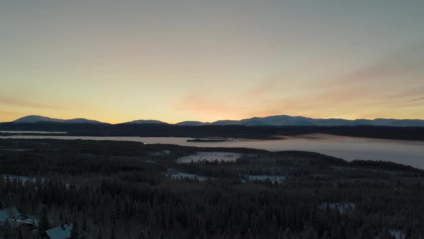 View of large area of land with trees being silhouetted against the sky at dusk