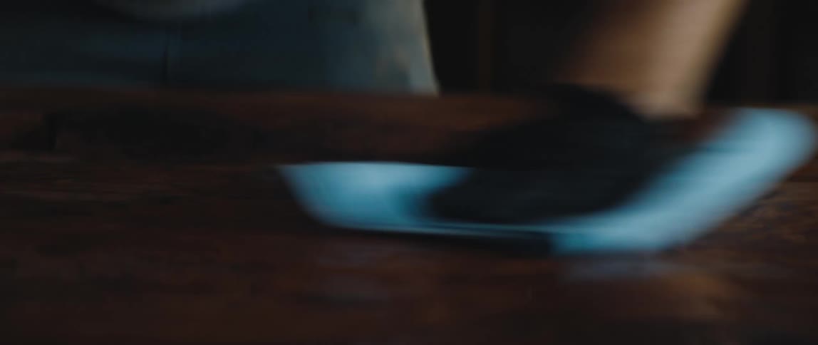 Man with jeans and black gloves wipes table with cloth