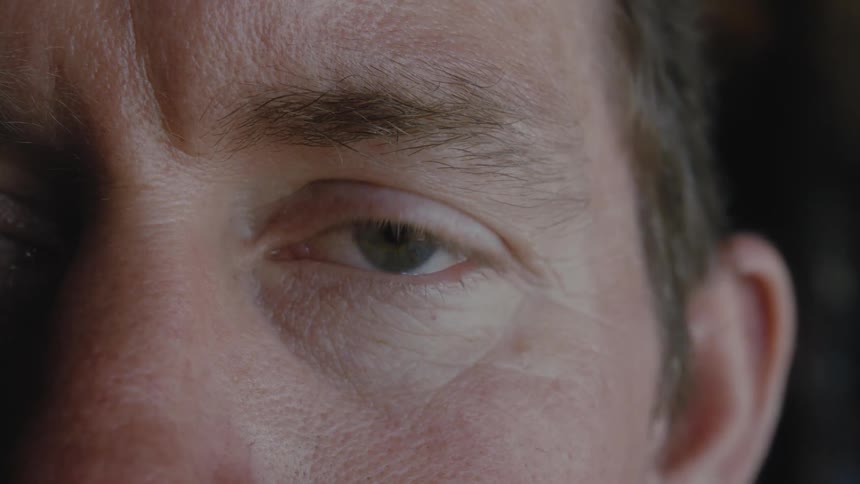 White man with green eye staring ahead and blinking