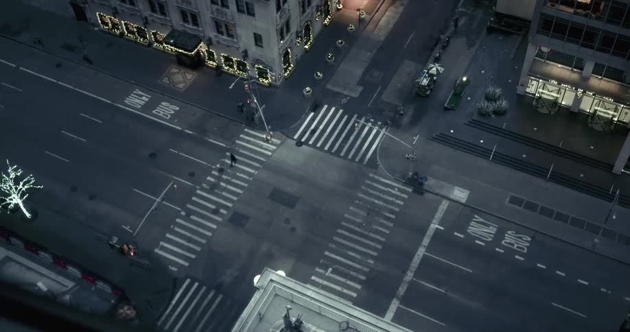 Birds eye view of pedestrian walking across crosswalk at dusk downtown in the city