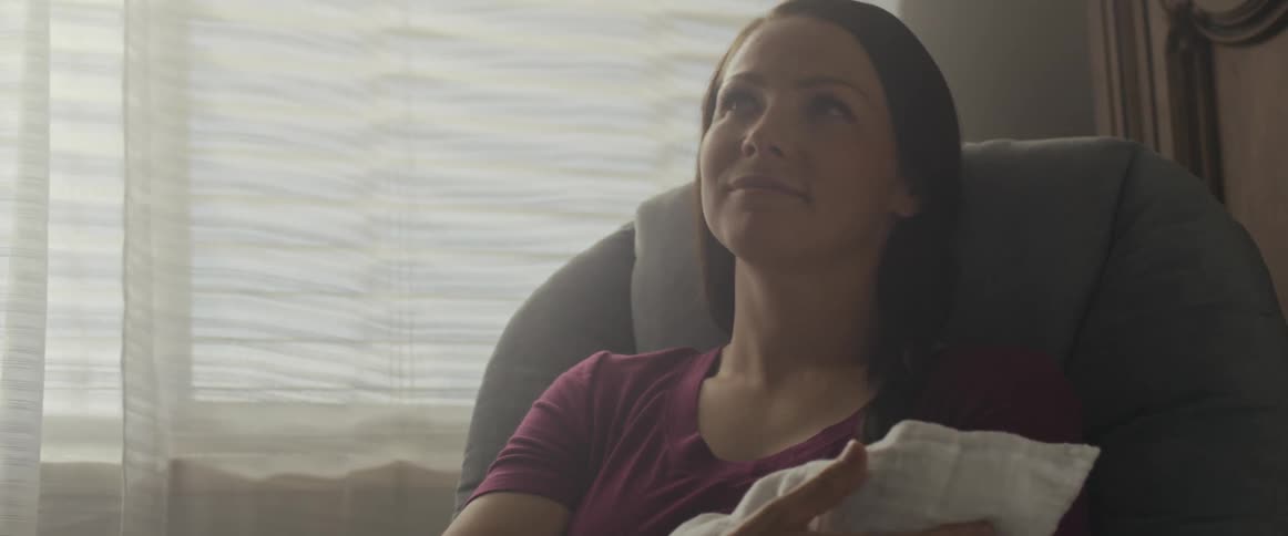 A mother is rocking her child in the chair and looks up in gratitude