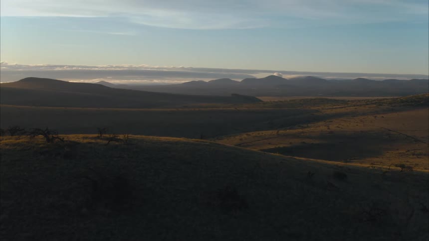 An aerial view of rolling hills in nature at sunrise