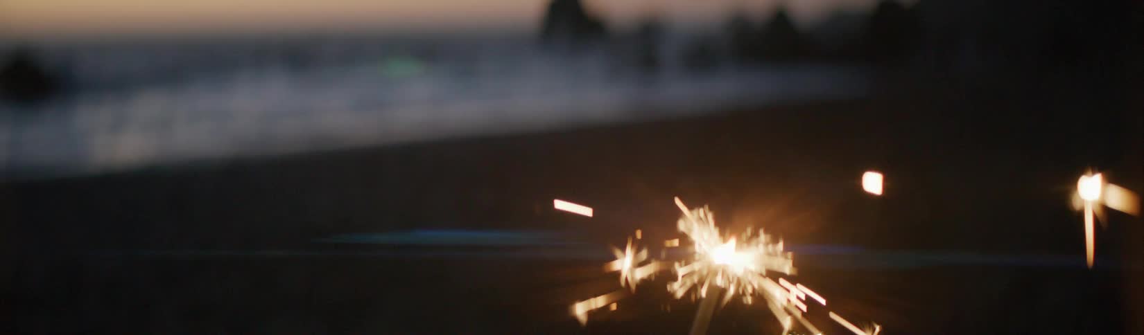 Sparkler stands out against sandy beach and red tinted horizon