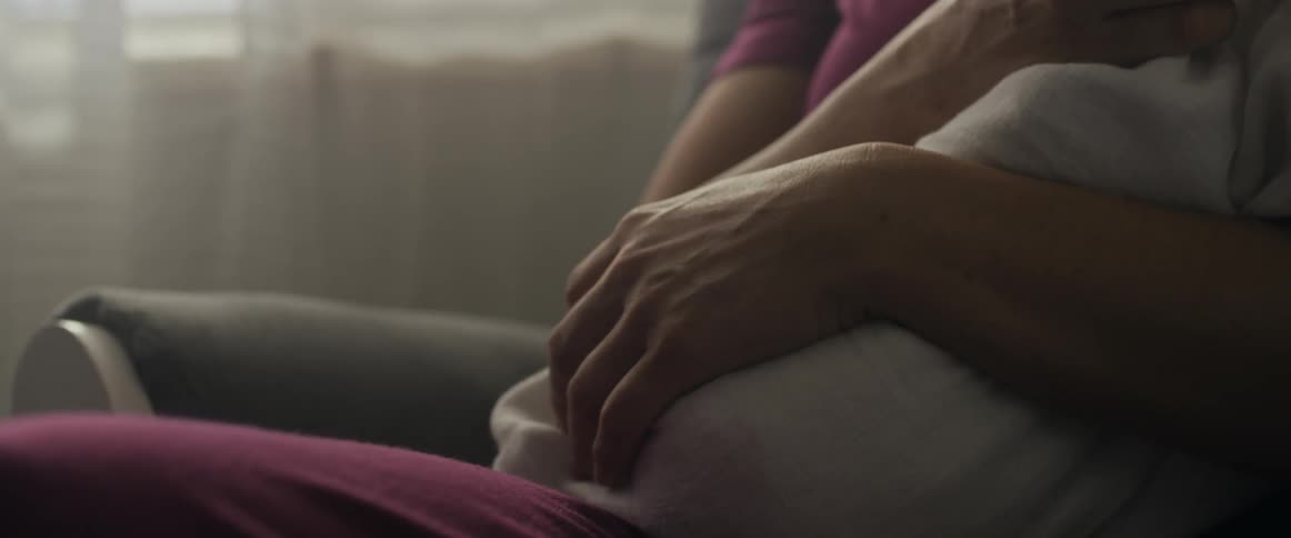 Close up of a mother holding a baby in her hands while sitting in a rocking chair at home