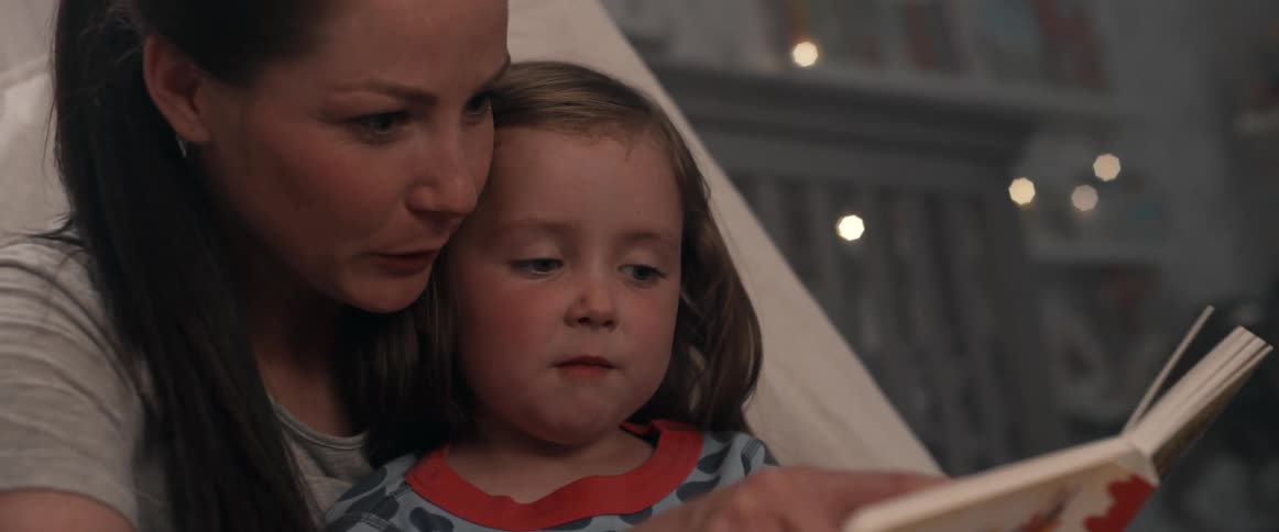 Mother reads daughter a book with her daughter sitting on her lap
