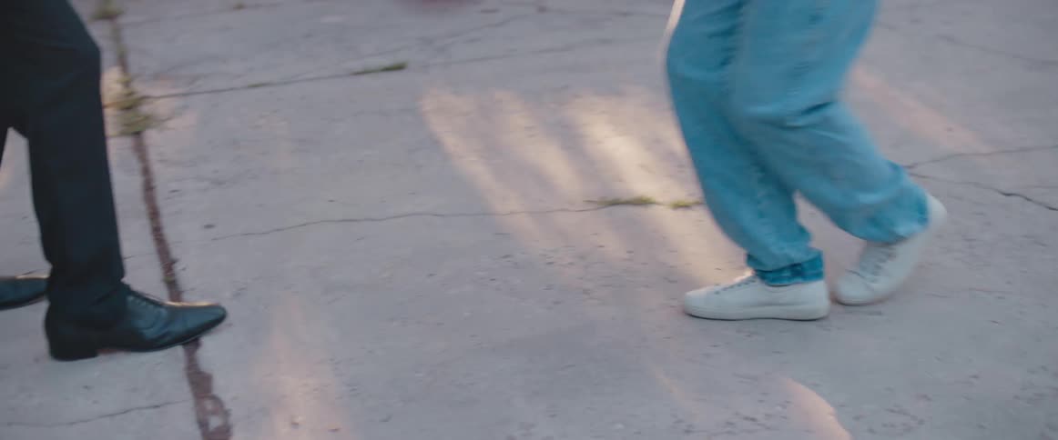 Adult male wearing business slacks and dress shoes plays basketball with youth