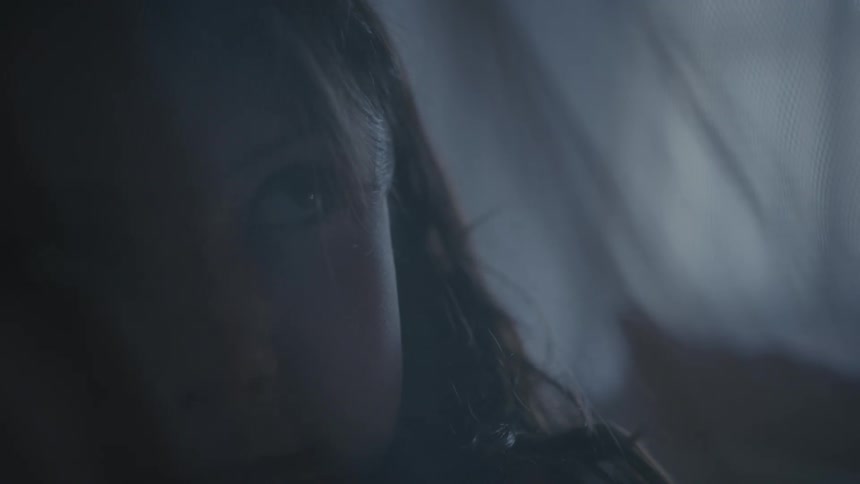 Close up of a young woman opening her eyes and looking up startled inside a dimly lit room