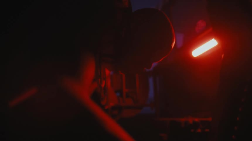 A man grabs a rag as he works outside under a glowing red light