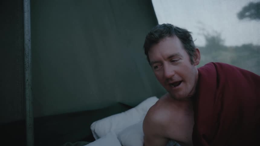 Man and woman waking up inside a camping tent
