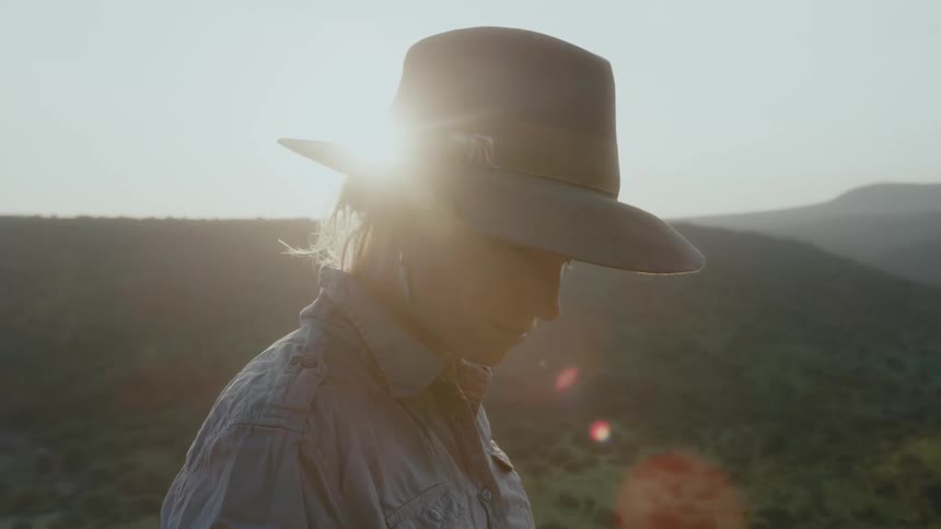 A woman is standing by a hill