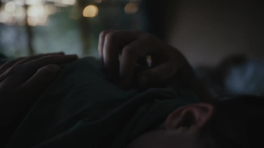Father caressing his sons back who is lying facing down on his belly in the bed
